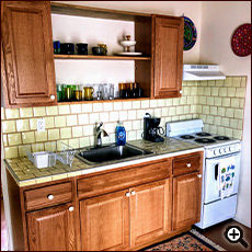 The Strawbale Studio kitchen area with sink, oven, and cupboards at Cat Mountain Lodge